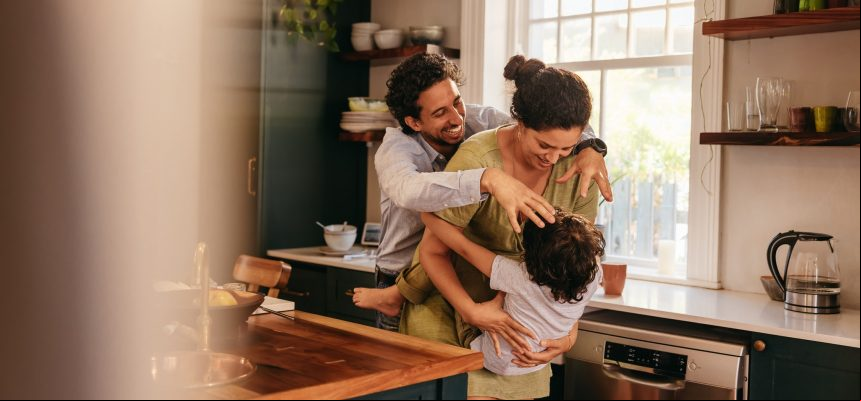 Parents playing with their son in the kitchen. Two happy parents laughing and having fun with their young son at home. Family of three spending some quality time together.